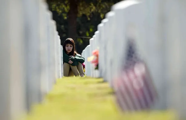 Giselle Dela Garza visits the grave site of her grandfather, Navy veteran Paul Dela Garza, during a Veteran's Day event at Fort Sam Houston National Cemetery, Thursday, November 11, 2021, in San Antonio. (Photo by Eric Gay/AP Photo)