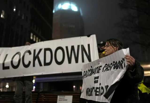 A protestor holds a banner during a small anti-COVID restriction demonstration in the Hague, the Netherlands, Saturday, December 18, 2021. Dutch government ministers are meeting Saturday to discuss advice from a panel of experts who are reportedly advising a toughening of the partial lockdown that is already in place to combat COVID-19. (Photo by Peter Dejong/AP Photo)