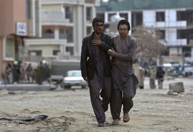 An Afghan man helps an injured man at the site of an attack by Taliban insurgents in Kabul March, 28, 2014. A group of Afghan Taliban insurgents forced their way into a guesthouse used by foreigners in an upscale residential part of the capital Kabul on Friday, police said. (Photo by Omar Sobhani/Reuters)