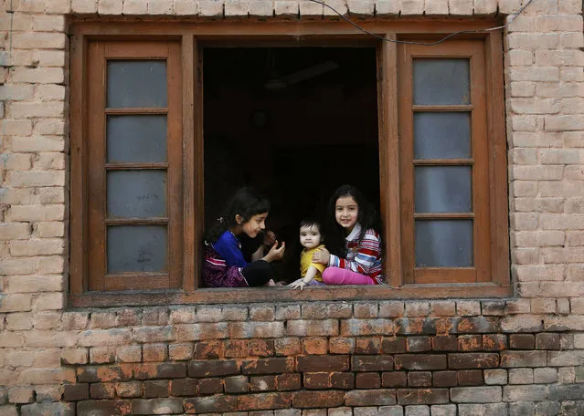Kashmiri children sit on the window of their house during restrictions in Srinagar, Indian controlled Kashmir, Monday, July 8, 2019. Authorities imposed restrictions in some parts of Srinagar after separatists called for a strike making the death anniversary of Kashmiri rebel leader Burhan Wani who was killed by Indian security forces on July 8, 2016. (Photo by Mukhtar Khan/AP Photo)