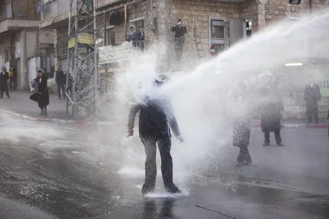 An ultra-Orthodox Jew gets hit by a police water canon during a protest against Israeli army conscription, in Jerusalem, Wednesday, March 15, 2017. Ultra-Orthodox Jews have for years been exempt from military service, which is compulsory for Jewish Israelis. The arrangement has caused widespread resentment among Israel's secular majority. The ultra-Orthodox claim the military will expose their youth to secularism and undermine their devout lifestyle. (Photo by Oded Balilty/AP Photo)