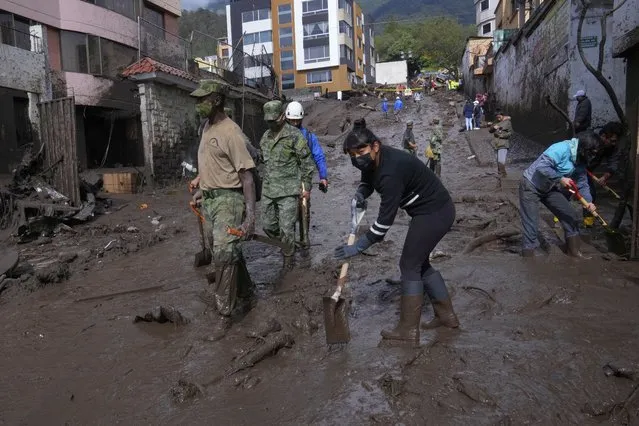Residents and soldiers work to clear mud from streets after a rain-weakened hillside collapsed and brought waves of mud over La Gasca area of Quito, Ecuador, Tuesday, February 1, 2022. (Photo by Dolores Ochoa/AP Photo)