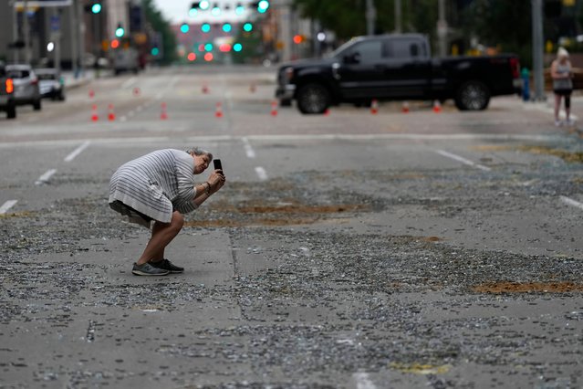 Cherly Herpich takes a photograph of a downtown building with blown out window in the aftermath of a severe thunderstorm Friday, May 17, 2024, in Houston. Thunderstorms pummeled southeastern Texas on Thursday killing at least four people, blowing out windows in high-rise buildings and knocking out power to more than 900,000 homes and businesses in the Houston area. (Photo by David J. Phillip/AP Photo)