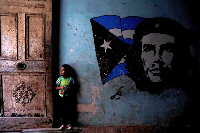 Jefrey, 6 years old, stands next to a hand-painted mural depicting Ernesto «Che» Guevara and the Cuban flag at the entrance of a building in Havana, Cuba, February 3, 2022. (Photo by Amanda Perobelli/Reuters)