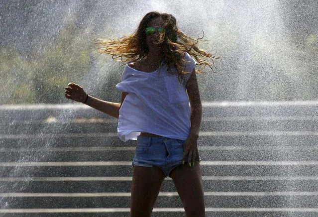 Woman cools off in a sprinkler on the Vistula river bank in Warsaw during a hot summer day July 7, 2015. The temperature in Poland reached around 30 degrees Celsius today. (Photo by Kacper Pempel/Reuters)