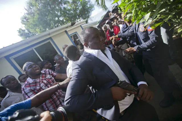 Ruling party Senator Willot Joseph holds a gun as he arrives to parliament for a vote to ratify Fritz William Michel's nomination as prime minister in Port-au-Prince, Haiti, Monday, September 23, 2019. Opposition members confronted ruling-party senators, and Joseph pulled a pistol when protesters rushed at him and members of his entourage. The vote was cancelled. (Photo by Dieu Nalio Chery/AP Photo)