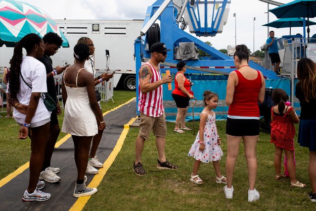 People wait to ride the ferris wheel at an annual carnival to celebrate July 4th at Clawson Park, Michigan, U.S., July 4, 2024. (Photo by Emily Elconin/Reuters)