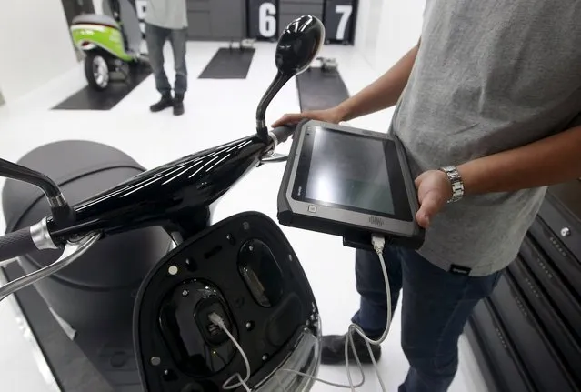 A mechanic examines a Gogoro Smartscooter which is connected to a tablet, in its shop in Taipei, Taiwan, July 6, 2015. (Photo by Pichi Chuang/Reuters)