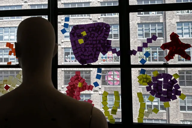 A mannequin stands near images created with Post-it notes in windows at 200 Hudson street in lower Manhattan, New York, U.S., May 18, 2016. (Photo by Mike Segar/Reuters)