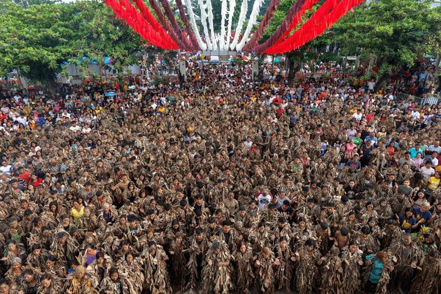 Catholic devotees covered in mud and dried leaves gather at church grounds for a holy mass during the Taong Putik Festival (Mud People) in Bibiclat village, Aliaga town in Nueva Ecija province, Philippines, 24 June 2024. The early morning ritual of the Mud People is followed by a holy mass to honor the feast day of Saint John the Baptist, as devotees give thanks and pray for more blessings in life. (Photo by Rolex Dela Pena/EPA/EFE)