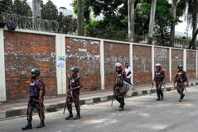 Security personnel walk past the headquarters of state broadcaster Bangladesh Television, after students set it on fire amid the ongoing anti-quota protest in Dhaka on July 19, 2024. (Photo by Munir Uz Zaman/AFP Photo)