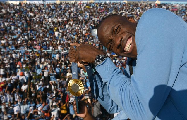 Olympic gold medallist, Botswana's Letsile Tebogo, who won the men's 200m athletics event during the Paris 2024 Olympic Games, holds his gold medal as he arrives on an open bus at the Botswana national Stadium during a welcoming ceremony in Gaborone on 13 August 2024. (Photo by Monirul Bhuiyan/AFP Photo)