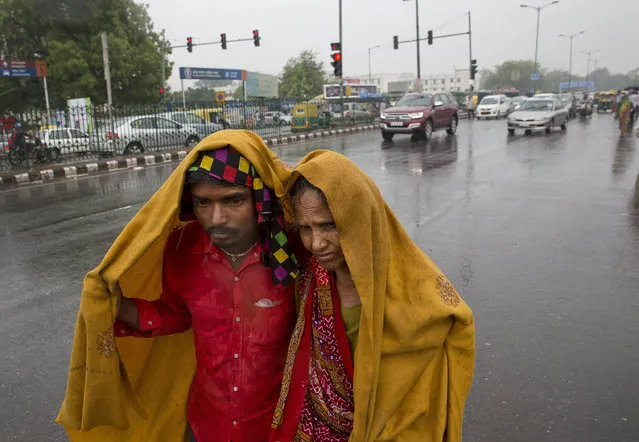 A son covers her mother with a shawl in the rain, as they look for transportation in New Delhi, India, Monday, May 30, 2016. The city has been witnessing light rain and dust storms continuously for the past week, which has brought down temperatures from days of a relentless summer heat wave. (Photo by Manish Swarup/AP Photo)