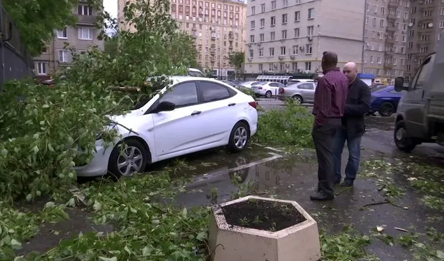 In this grab taken from video, men stand near to a vehicle crushed by branches from a fallen tree, in a residential area of Moscow, Russia, Monday, May 29, 2017. Thunderstorms and strong winds buffeted Moscow and its surrounding areas on Monday, killing 11 people and injuring dozens, Russian officials said.﻿﻿ ﻿(Photo by AP Photo)