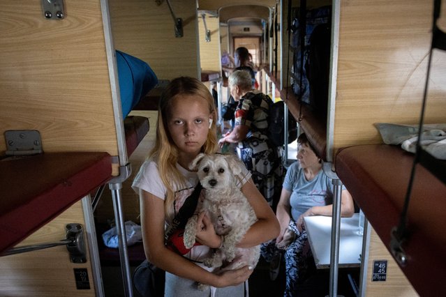 A girl holds her dog as she stands on an evacuation train as she flees with her family from Russian troop advances in Pokrovsk, Ukraine on August 22, 2024. (Photo by Thomas Peter/Reuters)