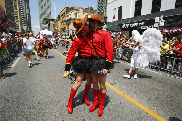 Two men dressed as Royal Canadian Mounted Police (RCMP) officers kiss during the “WorldPride” gay pride Parade in Toronto, June 29, 2014. Toronto is hosting WorldPride, a week-long event that celebrates the lesbian, gay, bisexual and transgender (LGBT) community. (Photo by Mark Blinch/Reuters)