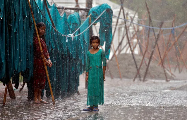 Girls stand in monsoon rains beside an open laundry in New Delhi, India, June 21, 2017. (Photo by Cathal McNaughton/Reuters)
