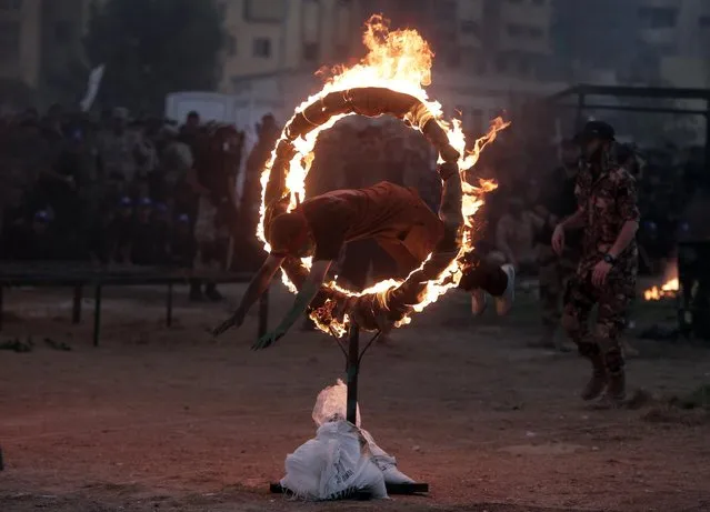 A young Palestinian jumps through a fire ring as part of a graduation ceremony of the Hamas, Liberation Youth, military summer camp, in Gaza City, Wednesday, August 5, 2015. (Photo by Khalil HamraAP Photo)