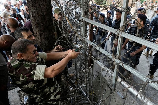 A retired Lebanese soldier removes the barbed wires that set by security forces for blocking protesters to reach the government palace, during a protest demanding an increase in their monthly retirement pay, decimated in the economic meltdown, in Beirut, Lebanon, Tuesday, September 10, 2024. (Photo by Bilal Hussein/AP Photo)