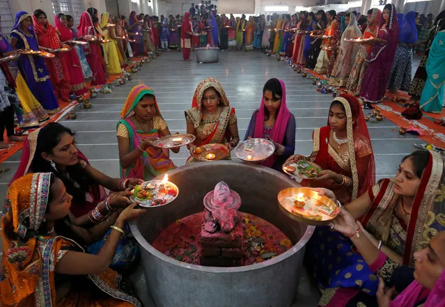 Hindu women perform a ritual known as Aarti around a Shivling (a symbol of Lord Shiva) on the last day of Jaya Parvati Vrat festival in Ahmedabad, India, July 10, 2017. (Photo by Amit Dave/Reuters)