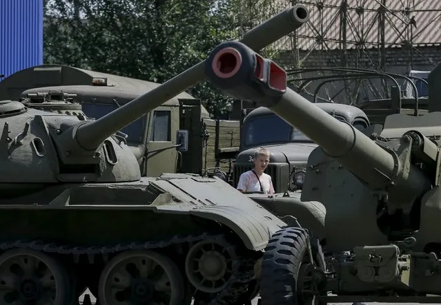 A visitor looks at an old soviet tank and cannon at Phaeton museum in Zaporizhia, Ukraine, August 11, 2015. The museum stopped the restoration works of their collection of about 120 retro autos and motorcycles to help the Ukrainian army to restore military vehicles and equipment which will be used in the conflict in Ukraine eastern regions. (Photo by Gleb Garanich/Reuters)