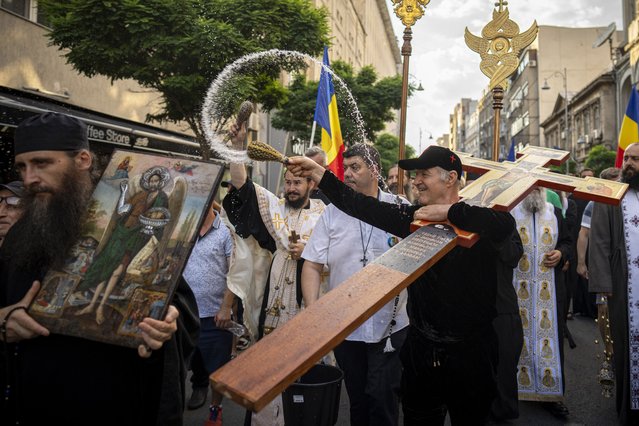 Former politician George Becali sprinkles holy water, while leading during a small religious procession meant to perform a “cleansing”, according to participants, of the route taken by the Bucharest Pride Parade which took place the day before in Bucharest, Romania, Sunday, July 30, 2023. The pride parade was the largest to date in the Romanian capital with more than twenty thousand participants calling for legal rights for gay people, like civil partnership, marriage or the right to adopt a child. (Photo by Andreea Alexandru/AP Photo)