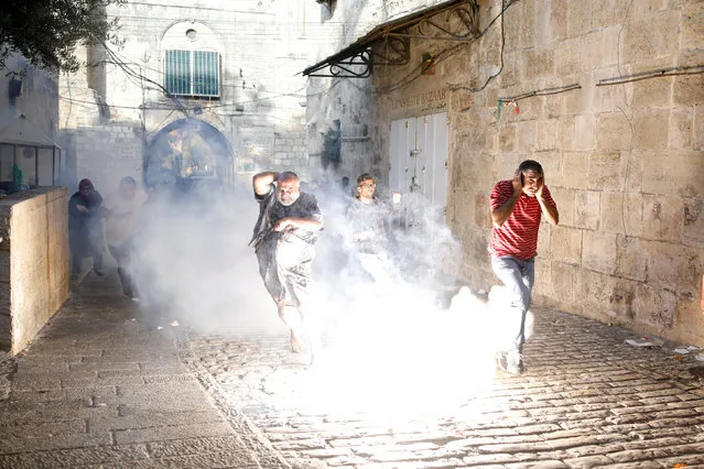 Palestinians react as a stun grenade explodes in a street at Jerusalem's Old city outside the compound known to Muslims as Noble Sanctuary and to Jews as Temple Mount, after Israel removed all security measures it had installed at the compound July 27, 2017. (Photo by Amir Cohen/Reuters)