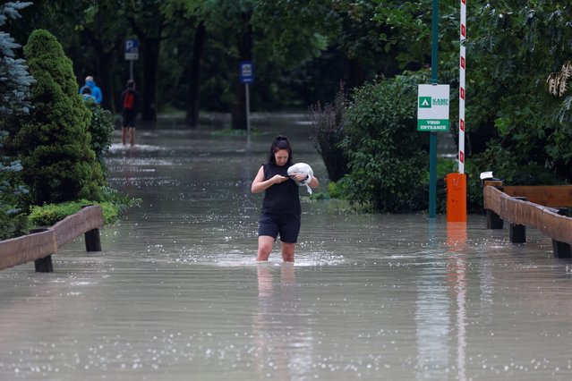 A woman wades in water during a flood in Kamnik, Slovenia on August 4, 2023. (Photo by Borut Zivulovic/Reuters)