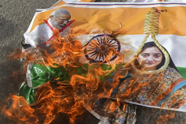 Protestors burn a poster with pictures of India's Prime Minister Narendra Modi and former Bharatiya Janata Party spokeswoman Nupur Sharma during a demonstration over her remarks on the Prophet Mohammed, in Karachi on June 9, 2022. (Photo by Asif Hassan/AFP Photo)