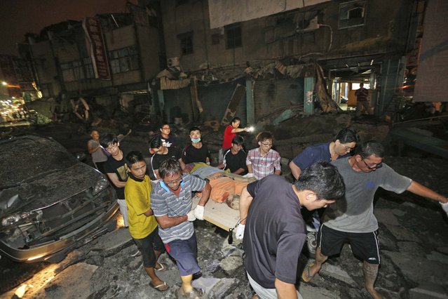 The body of a victim killed in a gas explosion from an underground gas leak is carried from the rubble in a main street in Kaohsiung, Taiwan, early Friday, August 1, 2014.  A massive gas leakage early Friday caused five explosions that killed several people and injured over 200 in the southern Taiwan port city of Kaohsiung. (Photo by AP Photo)