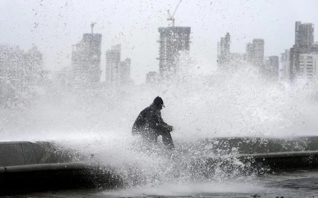 A man enjoys high tide waves on the Arabian Sea coast during monsoon rains in Mumbai, India, Wednesday, July 6, 2022. (Photo by Rajanish Kakade/AP Photo)