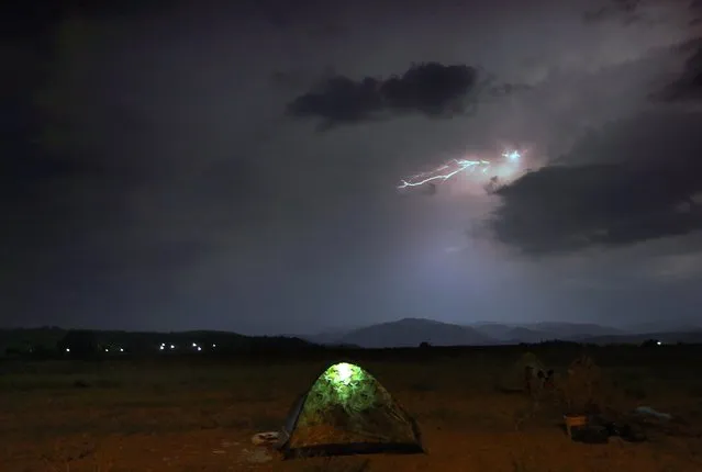 Refugees camp on a field as lightning strikes during a storm at the Greek-Macedonian border, near the village of Idomeni, August 21, 2015. (Photo by Yannis Behrakis/Reuters)