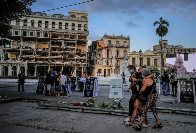 Relatives cry as they walk past photos of their deceased relatives during a vigil, at the site of a deadly explosion that destroyed the five-star Hotel Saratoga in Old Havana, Cuba, Friday, May 13, 2022. Cuban President Miguel Diaz-Canel declared an official day of mourning Friday for the victims of the May 6th explosion. (Photo by Ramon Espinosa/AP Photo)
