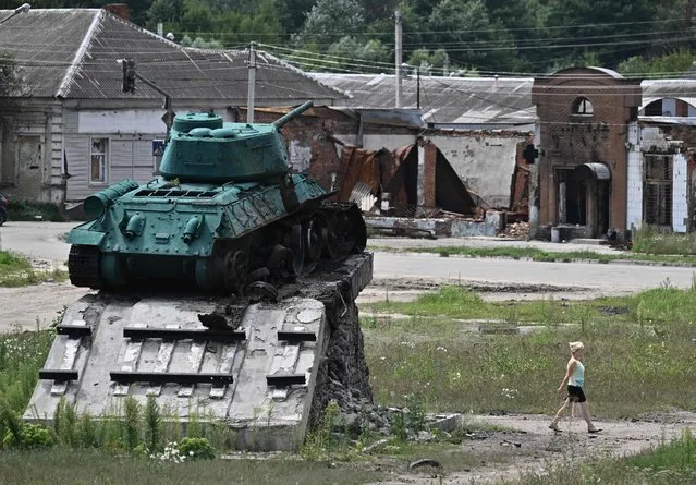 A woman walks past a damaged Soviet monument in the city of Trostyanets, Sumy region on August 1, 2022, amid the Russian invasion of Ukraine. (Photo by Genya Savilov/AFP Photo)