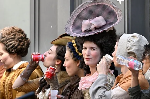 Extras on the set of a historical television series on Benjamin Franklin break for refreshments, as temperatures reach into the low 30s Centigrade, during filming in Paris on August 11, 2022. (Photo by Emmanuel Dunand/AFP Photo)