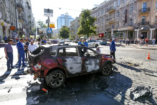 Forensic experts examine the wreckage of a burned car in Kiev, Ukraine, Wednesday, July 20, 2016. Pavel Sheremet, 44-year old Belarusian-born prominent journalist was killed in a car bombing in Ukraine's capital Kiev. (Photo by Sergei Chuzavkov/AP Photo)