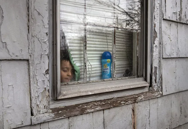 An undocumented Honduran immigrant, 4, sick and isolated with his family for the last two weeks, stands inside his bedroom window on March 30, 2020 in Mineola, New York. The nine immigrants who share a Long Island rental house self-quarantined after one became ill with fever, and the rest quickly followed. Most are largely recovered but never received tests for COVID-19. The coronavirus pandemic has been especially difficult for undocumented communities, who lack unemployment protections, health insurance and fear deportation if authorities know their whereabouts. (Photo by John Moore/Getty Images)