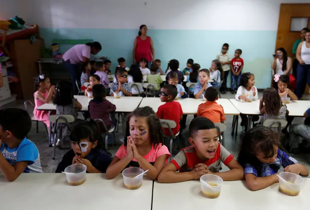 Students pray before eating their soup cooked for them during an activity for the end of the school year at the Padre Jose Maria Velaz school in Caracas, Venezuela July 12, 2016. (Photo by Carlos Jasso/Reuters)