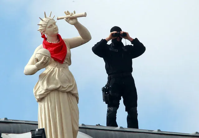 In this photo taken on Wednesday, July 27, 2016, a French police officers watches the festivities through binoculars on the roof of the town hall, during the opening night of the Bayonne festival, or “Fetes de Bayonne”, in Bayonne, southwestern France.  Bayonne, the cultural capital of the French Basque country, hosts the yearly traditional Bayonne festival from July 27-31, and is expected to attract about one million people this year from all over France, Spain, and other European countries. (Photo by Bob Edme/AP Photo)