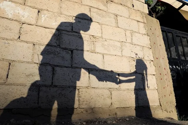 The shadow of a girl receiving a meal for iftar, or the evening meal, to break fast from a member of “Tkiyet Um Ali” humanitarian services center is cast on a wall in front of her family home in the city of Russeifa, during the holy fasting month of Ramadan, amid concerns over the spread of coronavirus disease (COVID-19), in Jordan, April 28, 2020. (Photo by Muhammad Hamed/Reuters)