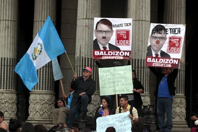 Protesters hold Guatemalan flag and placards of Manuel Baldizon, presidential candidate of opposition Renewed Democratic Liberty Party (LIDER), as they take part in a protest against what they say is the death of Guatemalan democracy in Guatemala City, September 5, 2015. Guatemala on Sunday will hold a presidential election. The placard at the center reads, “We demand reforms to the electoral law on political parties, democracy is more than a vote”. (Photo by Jose Cabezas/Reuters)