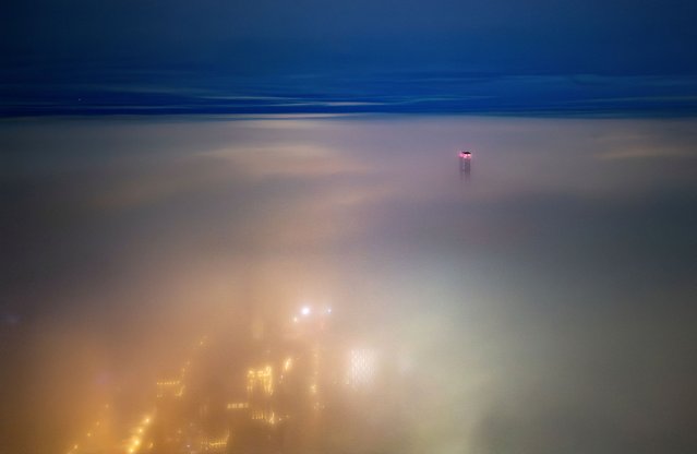 A drone view shows a tower of Abu Dhabi Plaza sticking out of a thick blanket of fog in Astana, Kazakhstan, on December 1, 2024. (Photo by Turar Kazangapov/Reuters)
