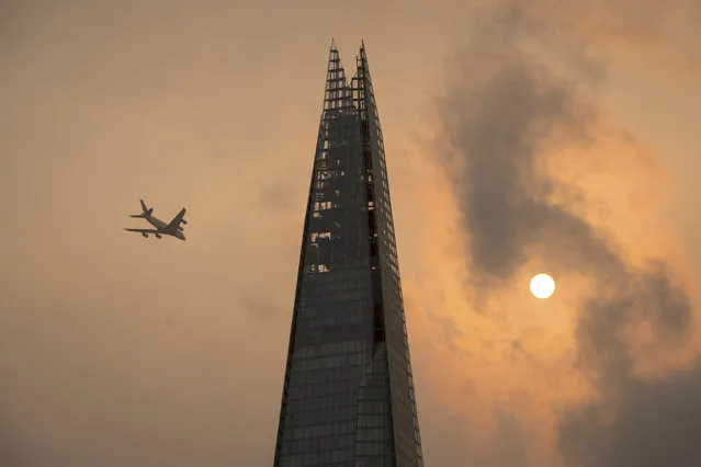 A plane flies past the Shard in central London, as the sky takes on an unusual orange colour caused by Hurricane Ophelia Monday October 16, 2017. The unusual occurrence was due to the remnants of the hurricane dragging in tropical air and dust from the Sahara. (Photo by Dominic Lipinski/PA Wire via AP Photo)