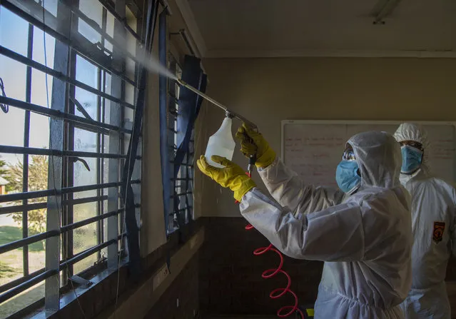 Disinfection team disinfect a classroom at Ivory Park Secondary School east of Johannesburg, South Africa, Thursday, May 28, 2020, ahead of the June 1, 2020, re-opening of Grade 7 and 12 learners to school. (Photo by Themba Hadebe/AP Photo)