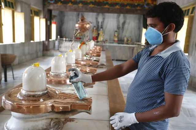 An employee of a temple sanitizes Shivlings in Prayagraj, India, Monday, June 8, 2020. Religious places, malls, hotels and restaurants open Monday after more than two months of lockdown as a precaution against coronavirus. (Photo by Rajesh Kumar Singh/AP Photo)