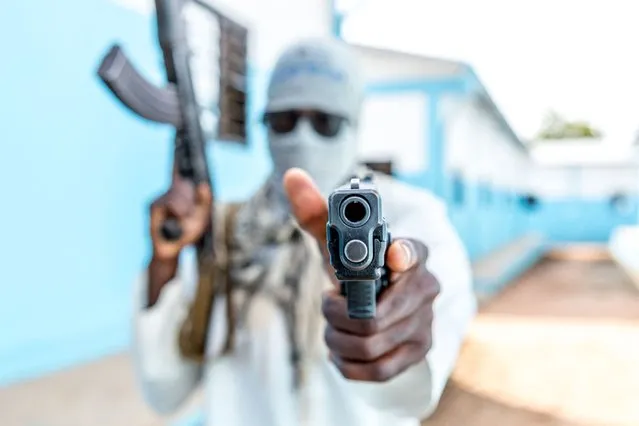 A Togolese policeman, disguised as a terrorist, brandishes his weapon on October 20, 2022 during an anti-terrorism exercise at the Peacekeeping Operations Training Center (CEOMP). (Photo by Yanick Folly/AFP Photo)