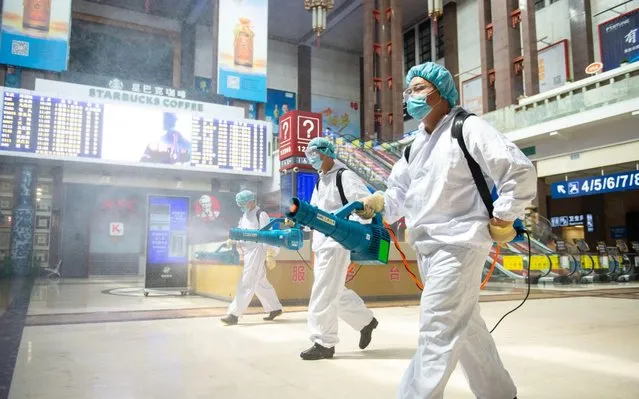 Workers wearing protective suits spray disinfectant at Beijing Railway Station on June 18, 2020 in Beijing, China. (Photo by Jian Tianyong/China News Service via Getty Images)