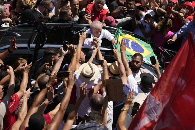 Former Brazilian President Luiz Inacio Lula da Silva, center, who is running for president again, hold hands with a supporter after voting in a presidential run-off election in Sao Paulo, Brazil, Sunday, October 30, 2022. (Photo by Andre Penner/AP Photo)