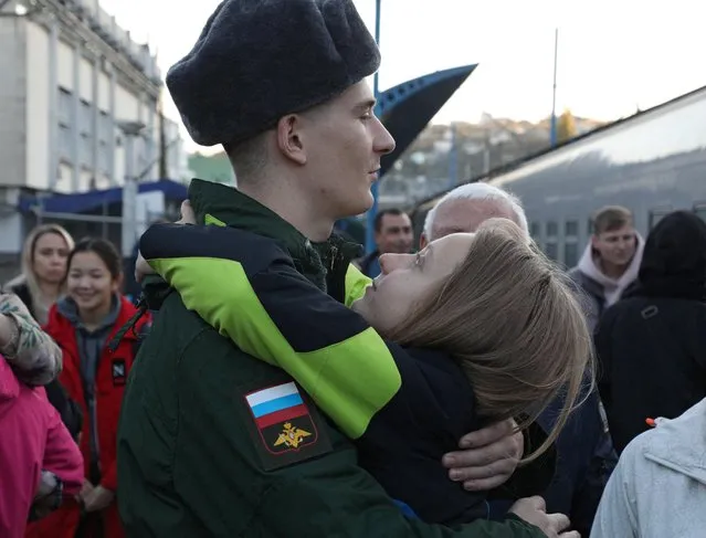 A conscript hugs a girl as he says goodbye to family members at a local railway station during departure for the garrisons, in Sevastopol, Crimea on November 9, 2022. (Photo by Alexey Pavlishak/Reuters)