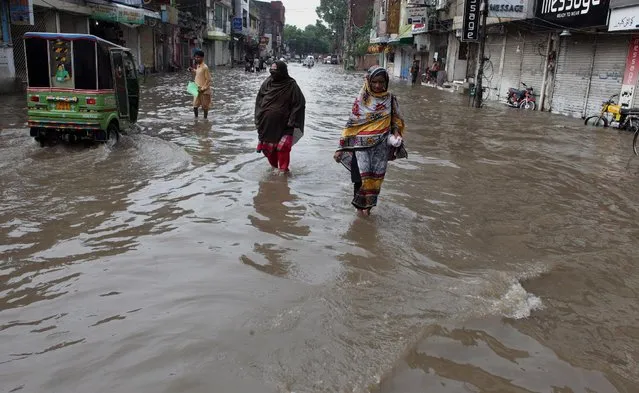 People wade through a flooded road after heavy rain fall in Lahore, Pakistan, Saturday, August 27, 2016. Heavy rain lashed Lahore causing several rain-linked accidents. (Photo by K.M. Chaudary/AP Photo)